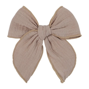 Detailed macro view of retro pink fabric bow hair clip with fine edge stitching texture