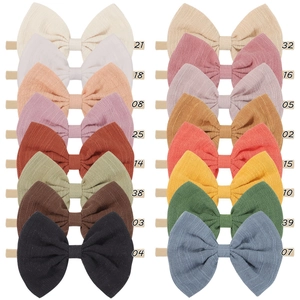 Collection of 16 colorful waffle-knit bow headbands for babies in various soft fabric shades