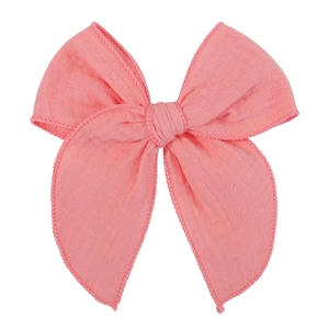Detail of pink fabric bow hair clip with textured weave and pom-pom trim edge