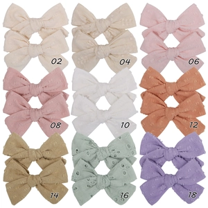 Detail view of 9 colors of cotton bow hair clips with embroidery and textured fabrics