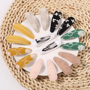 Detail view of 14-piece floral embroidered fabric snap hair clips in assorted colors