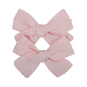 Detail view of two pink Swiss dot fabric bows with textured knot and soft material