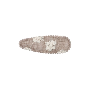Détail de la broderie de marguerite sur le tissu en tweed marron clair de la barrette