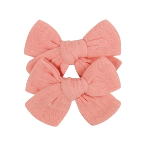 Close-up of two handmade fabric bow clips in textured peach cotton for kids