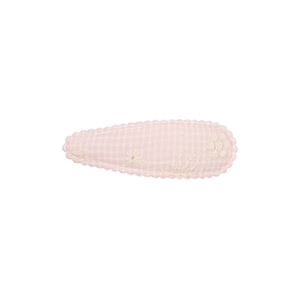 Détail d'une pince à cheveux rose en tissu avec broderie florale et bords festonnés