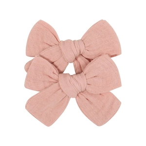 Detailed macro view of pink fabric bow hair clips for baby girls in soft linen texture