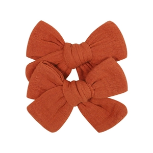 Detailed close-up of textured cotton muslin hair bows in deep orange for children