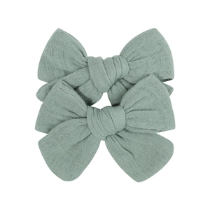 Close-up of two pieces fabric bow hair clips in sage green with soft woven texture