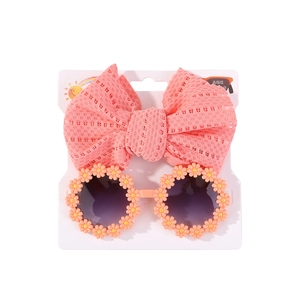 Nahaufnahme von rosa Spitzen-Stirnband und Gänseblümchen-Sonnenbrille für Babys auf Karte