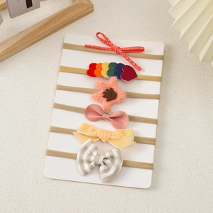 Detail showing a set of six elastic baby headbands with various colorful bows on a white card