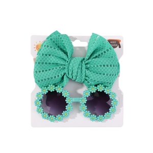 Nahaufnahme von mintgrünem Spitzen-Stirnband und Gänseblümchen-Sonnenbrille für Babys