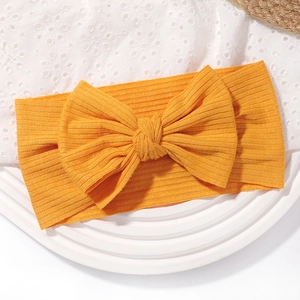 Détail de la texture côtelée et du gros nœud sur le bandeau bébé jaune moutarde