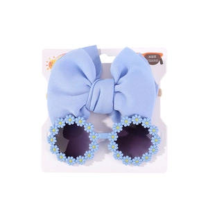Detail von hellblauem Schleifen-Haarband und Gänseblümchen-Sonnenbrille auf Verpackung