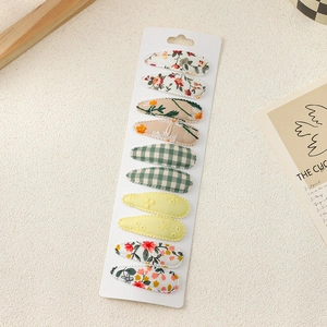 Close-up of 10-piece embroidered floral fabric hair clips on a white display card
