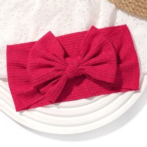 Gros plan d'un bandeau bébé en tissu côtelé rouge avec un grand nœud sur fond de dentelle