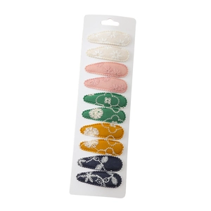 Set of 10 embroidered fabric hair clips in five colors on a white display card