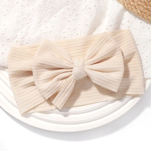 Gros plan sur la texture côtelée et le tricot doux du bandeau beige pour bébé