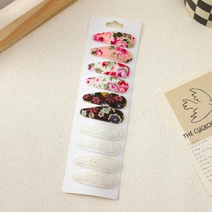 Set of ten fabric hair clips with floral and lace patterns on a white display card