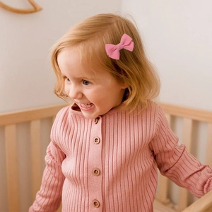 Pink striped grosgrain ribbon bow hair clip for toddlers in a warm lifestyle setting