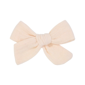 Detail of a creamy muslin fabric bow hair clip with textured double-layer gauze material