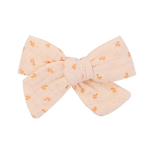 Detailed macro view of cream floral bow hair clip with textured linen fabric and soft patterns