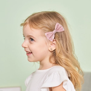 Gros plan d'un nœud papillon rose pailleté et de boucles d'oreilles cœur pour fille