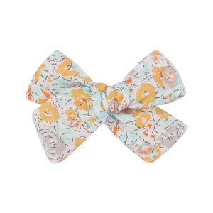 Close-up of floral print cotton fabric bow hair clip with yellow and orange patterns