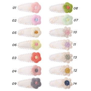 Detailed embroidery texture on 14 colorful floral hair clips with scalloped white fabric base