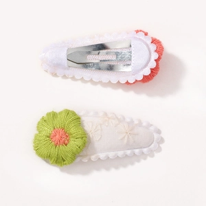 Close-up of dual-color embroidered floral hair clips with fabric wrapped metal bases