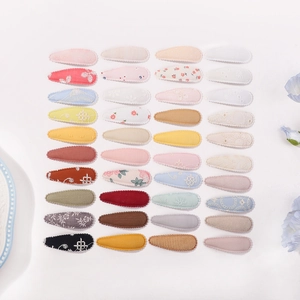 Détail de 40 barrettes en tissu aux motifs floraux et couleurs unies variées