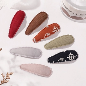 Vue détaillée de sept barrettes en tissu coloré avec bords ondulés et broderies délicates