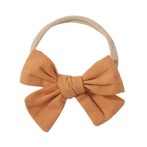 Detail view of a yellow fabric bow headband for babies with soft nylon elastic strap