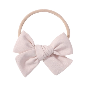 Detail of baby bow headband showing soft pink cotton texture and elastic nylon band