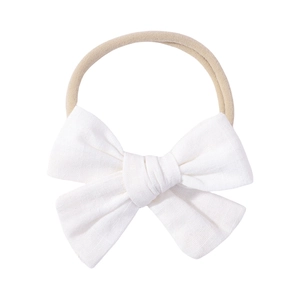 Detail of baby bow headband featuring white cotton linen fabric and beige elastic band