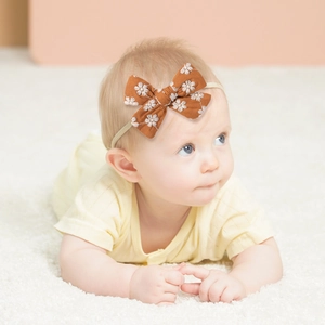 Infant bow headband in vintage brown with white floral embroidery on soft plush background