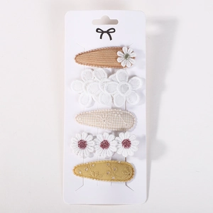 Detail of 5-piece floral fabric hair clips featuring lace embroidery and daisy patterns