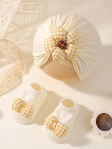 Détail du turban pour bébé et chaussettes avec fleur à carreaux jaunes et nœuds