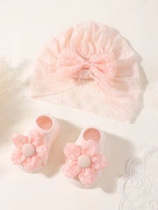 Détail de l'ensemble bandeau bébé rose avec nœud en dentelle et chaussettes à fleurs