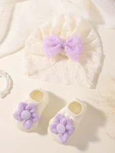 Détail de l'ensemble bonnet et chaussettes en dentelle blanche avec fleurs mauves