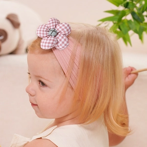 Détail d'un bandeau en nylon rose pour bébé avec une fleur en tissu à carreaux doux
