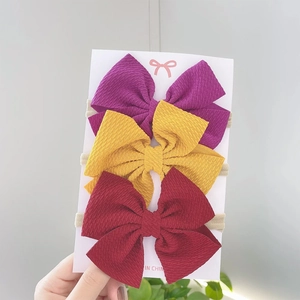 Detailed view of three baby bow headbands with ribbed texture on high-stretch nylon bands