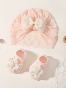 Détail de l'ensemble bonnet en dentelle rose avec nœud et chaussettes à fleurs