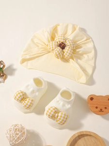 Détail de l'ensemble bonnet bébé jaune et chaussettes blanches avec nœuds vichy