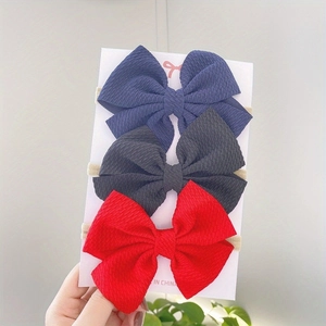 Detailed view of 3-piece waffle knit baby bow headbands in navy, black, and red set