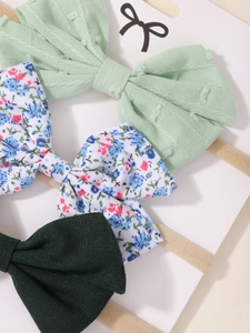 Detailed view of 3-piece floral and solid bow headbands set on a display card