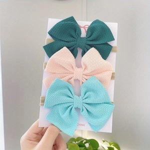 Close-up of three cute bow headbands for babies with ribbed texture on display card