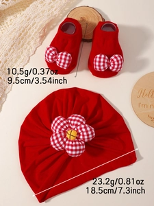 Détail d'un ensemble bonnet et chaussettes rouges pour bébé avec fleur et nœud à carreaux