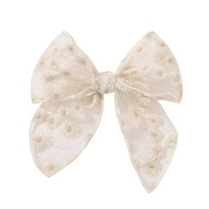 Détail du nœud à cheveux en maille blanc crème avec broderie de marguerites délicate