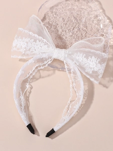 Détail du bandeau en dentelle blanche montrant la broderie florale et la texture du tissu
