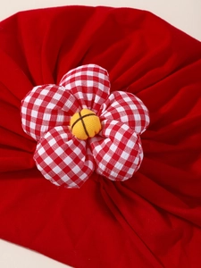 Vue macro détaillée du turban rouge pour bébé avec une grande fleur en tissu à carreaux